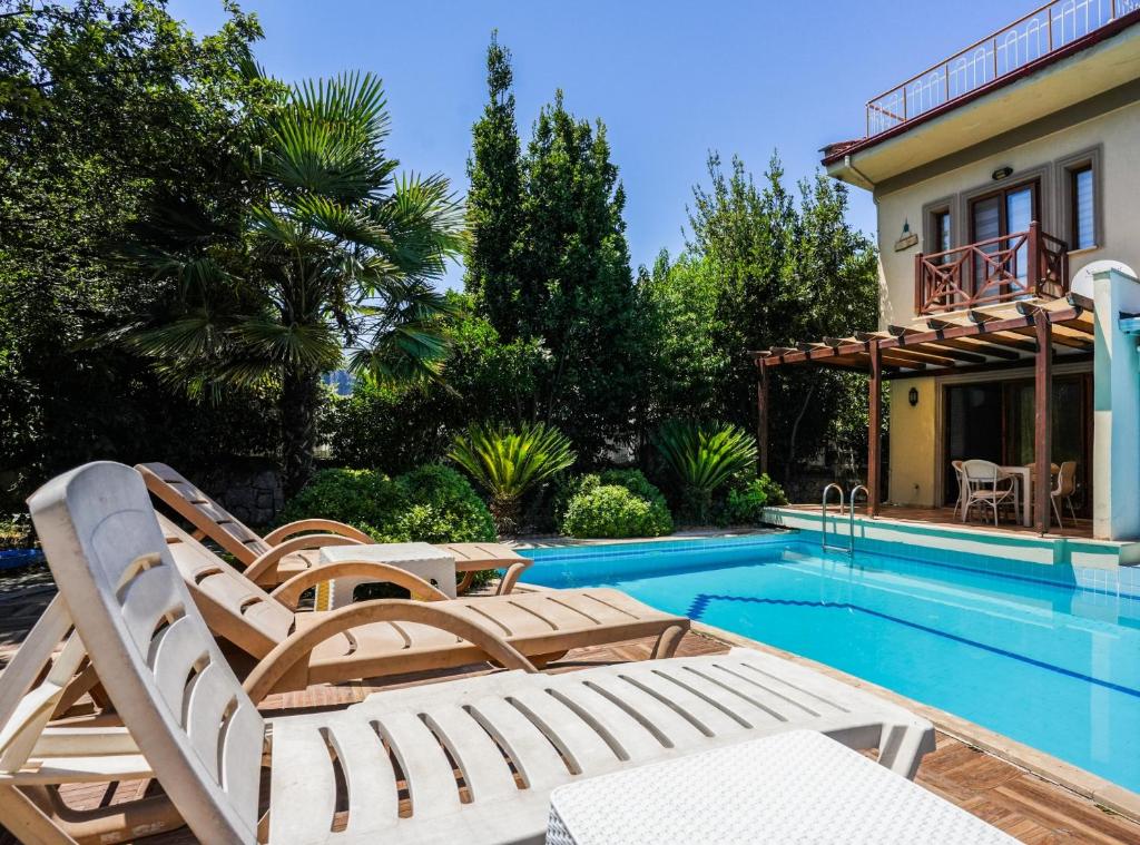 uma piscina com espreguiçadeiras ao lado de uma casa em Villa w Pool and Balcony 3 min to Dalyan River em Ortaca