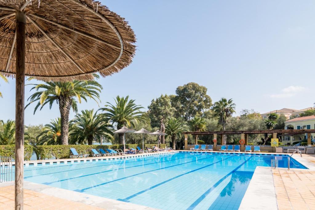 una piscina in un resort con ombrellone e sedie di Helion Resort a Gouviá