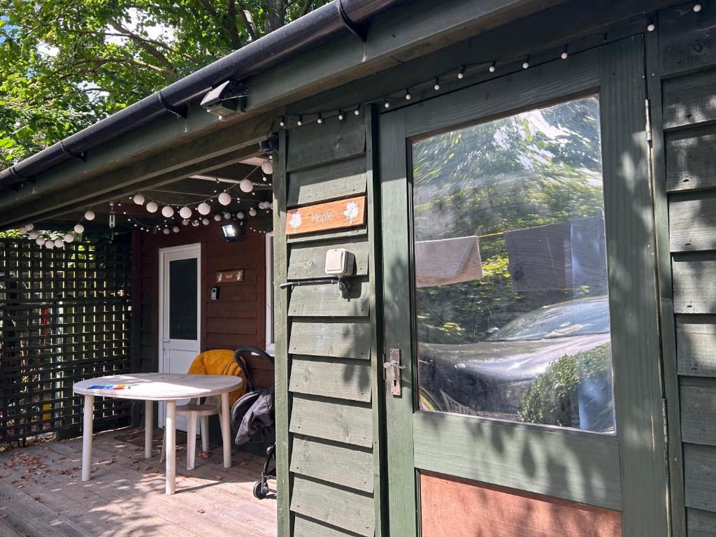 a green building with a table and a window at Maple by Paymán Club in Royston