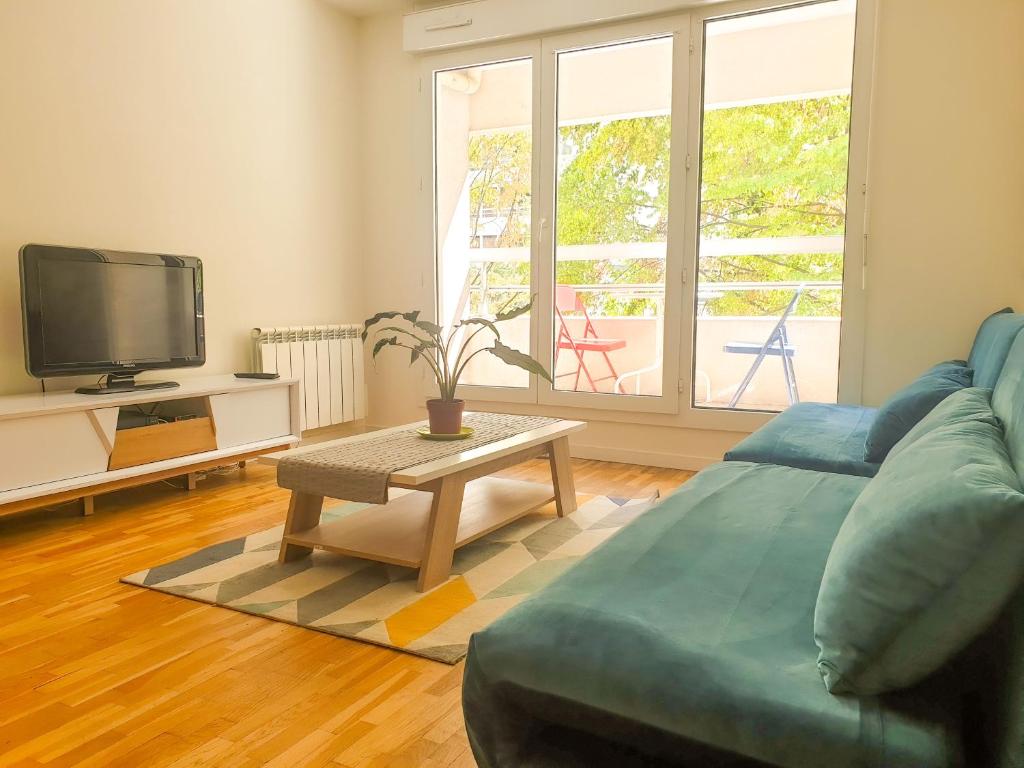 a living room with a couch and a table and a tv at ''Le Verlaine'' T2 au cœur de l'agglomération Lyonnaise in Villeurbanne