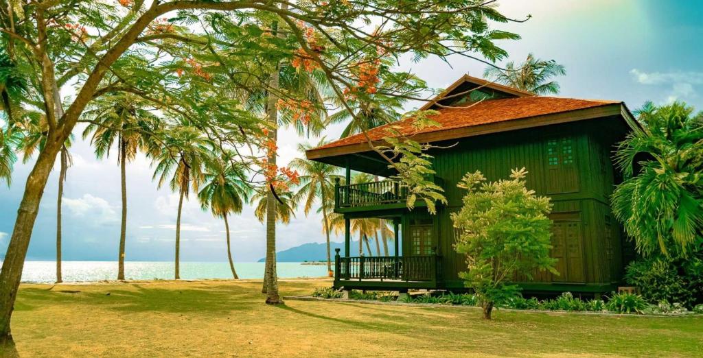 una casa verde con palmeras frente al océano en Pelangi Beach Resort & Spa, Langkawi en Pantai Cenang