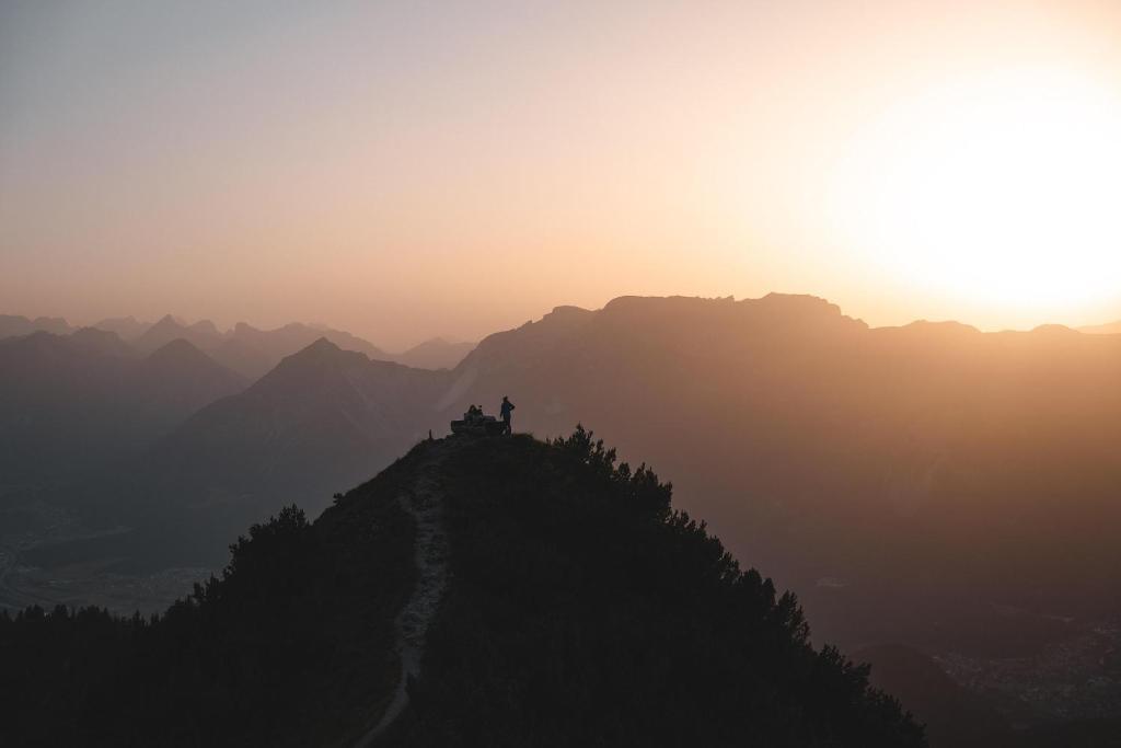osoba stojąca na szczycie góry o zachodzie słońca w obiekcie Riverside w Alpbach