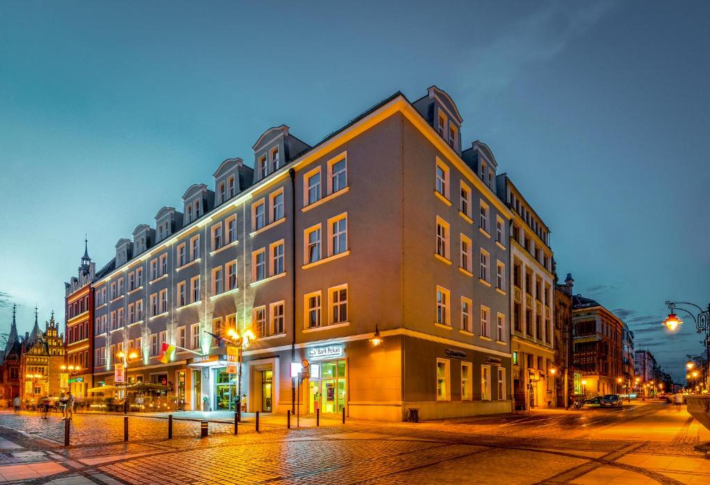 a large building on a city street at night at Korona Hotel Wroclaw Market Square in Wrocław