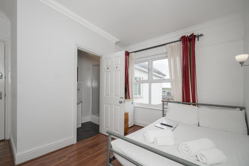 a white bedroom with a bed and a window at Flexistay Norbury Aparthotel in London
