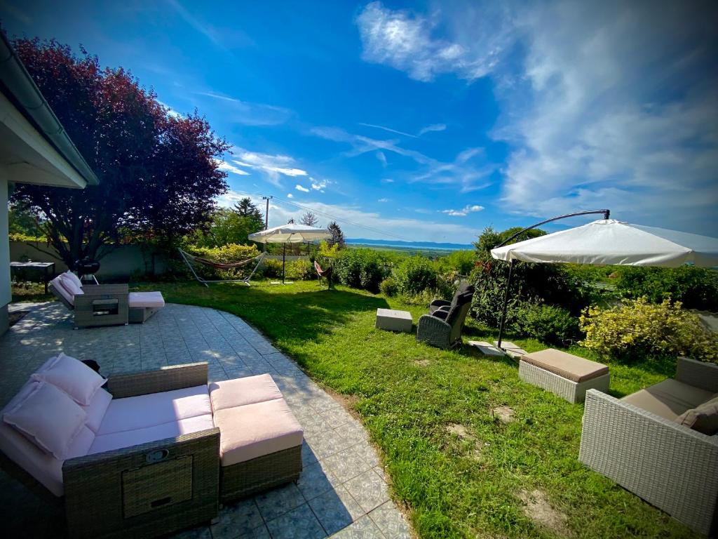 Un patio con sofás y una sombrilla en el césped. en Villa Sunset Garden, en Siófok