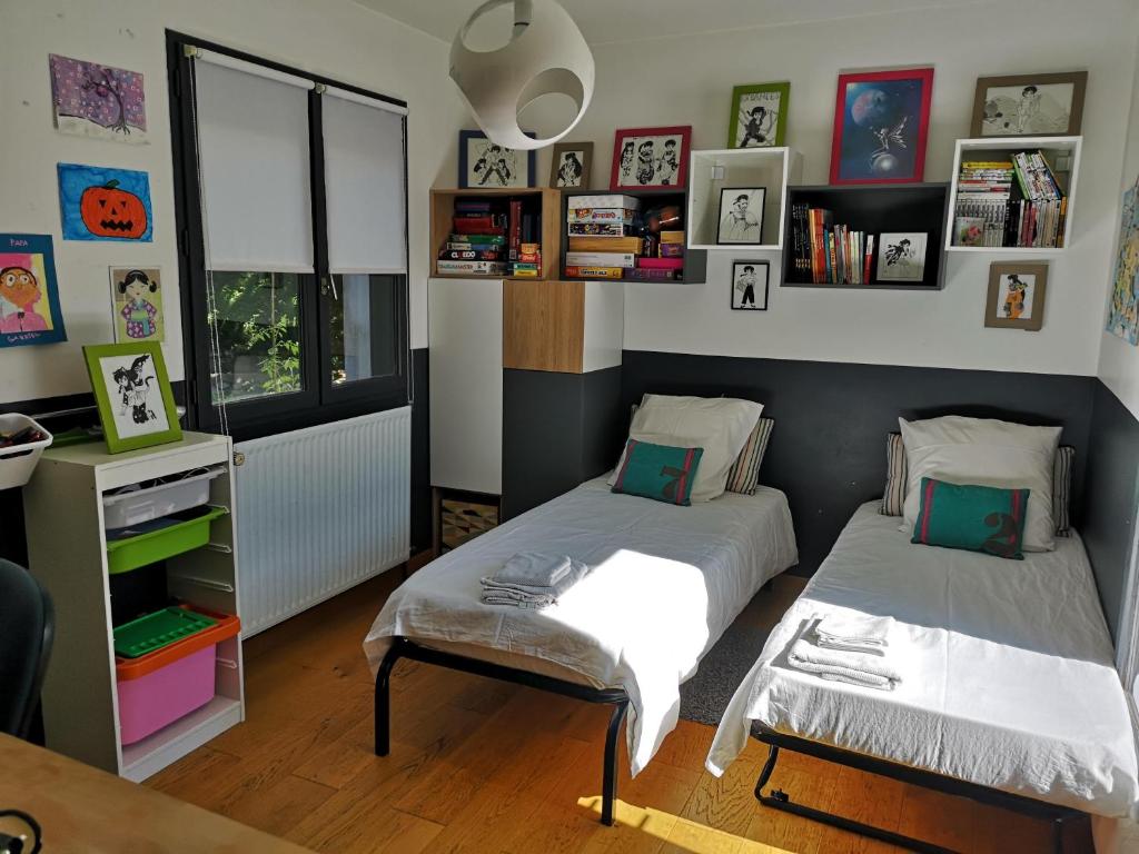 two beds in a room with bookshelves at VILLA MONTPELLIER in Montpellier
