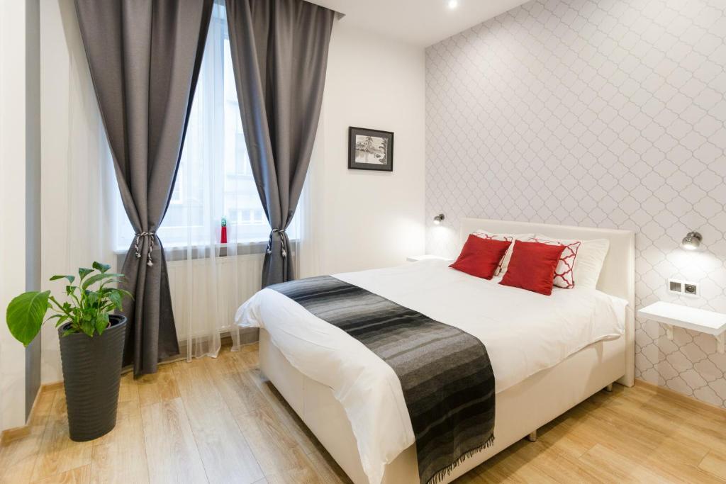 Un dormitorio con una cama con almohadas rojas y una ventana en Kazimierz Residence, en Cracovia