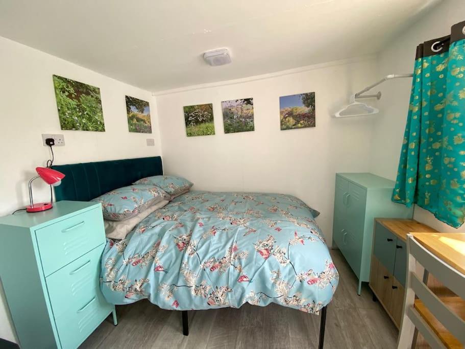 a bedroom with a bed with a blue comforter at Guest house Truro garden retreat in Kenwyn