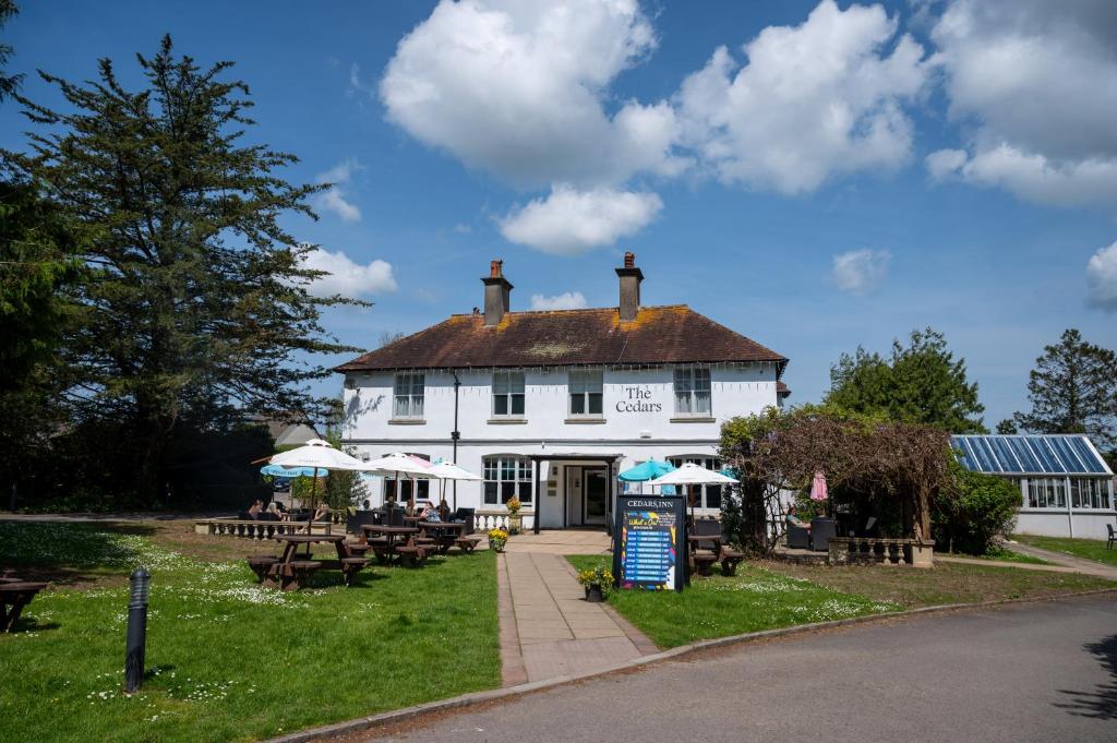 un bâtiment blanc avec des tables et des parasols devant lui dans l'établissement Cedars Inn by Greene King Inns, à Barnstaple