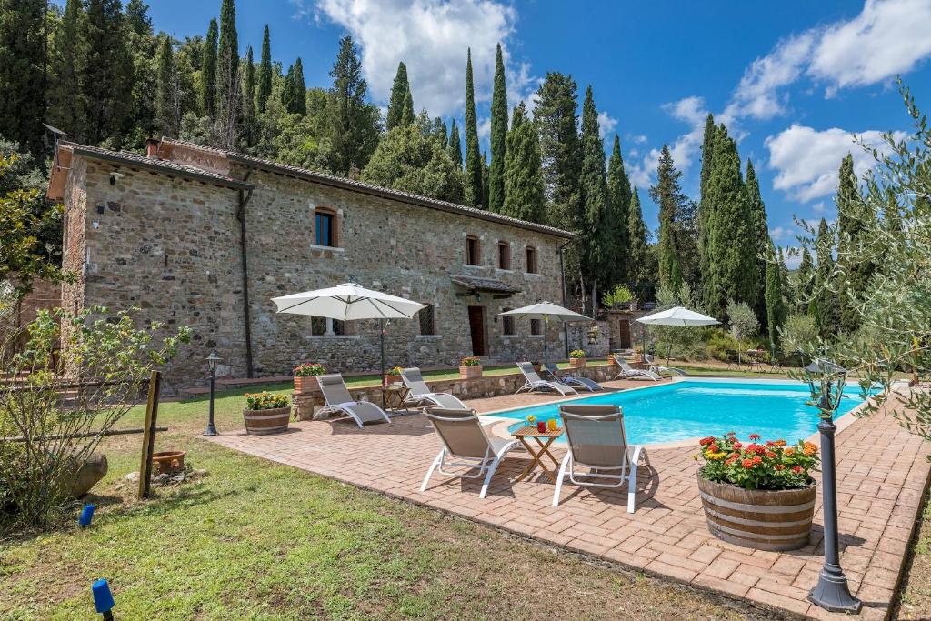 a pool with chairs and umbrellas in front of a building at PODERE MONTIONI 6&2, Emma Villas in Rapolano Terme