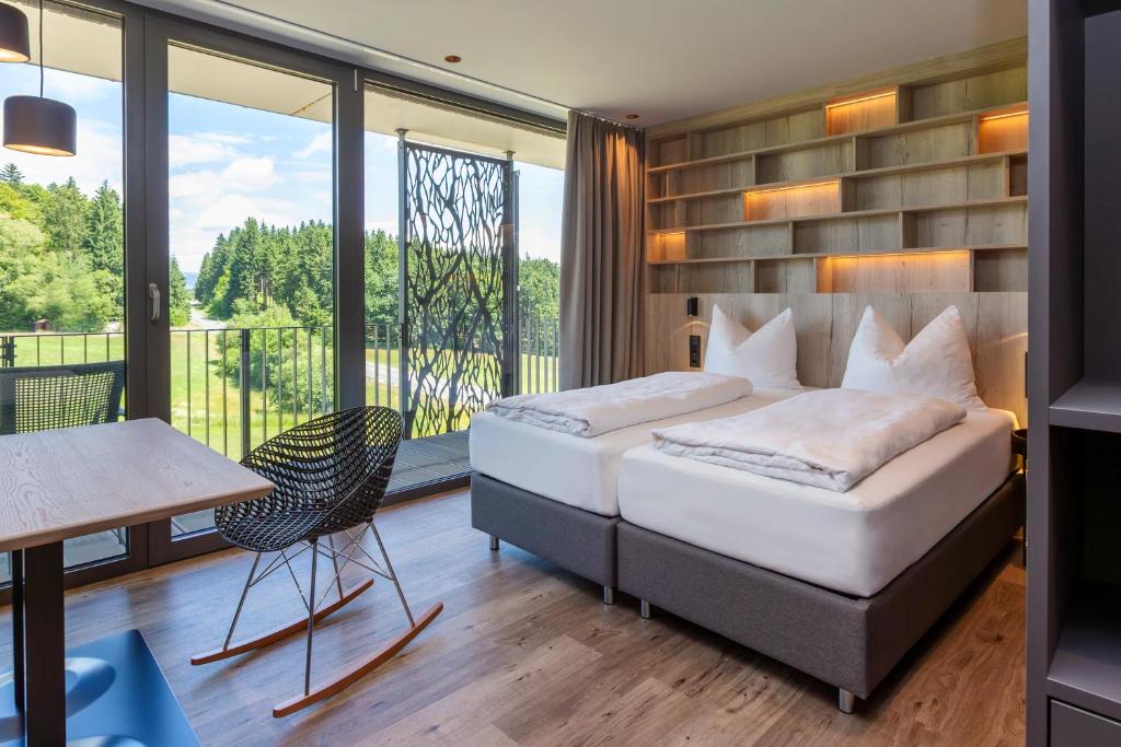 1 dormitorio con cama, mesa y balcón en Workation by Reischlhof, en Wegscheid