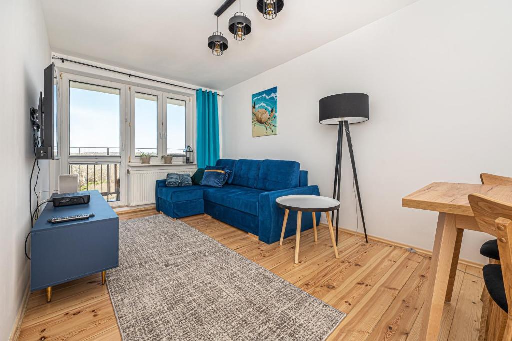 ein Wohnzimmer mit einem blauen Sofa und einem Tisch in der Unterkunft Apartament Crab Sopot Kamienny Potok in Sopot