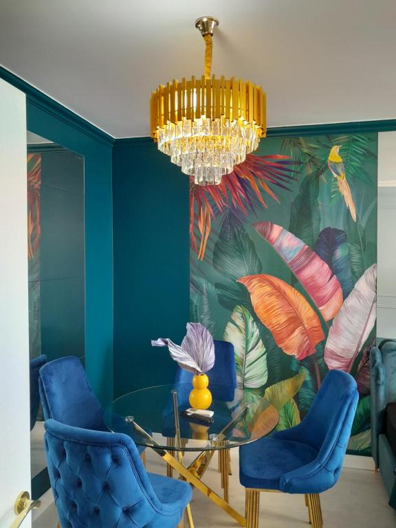 een eetkamer met een kroonluchter en blauwe stoelen bij Luxury Home in Oradea