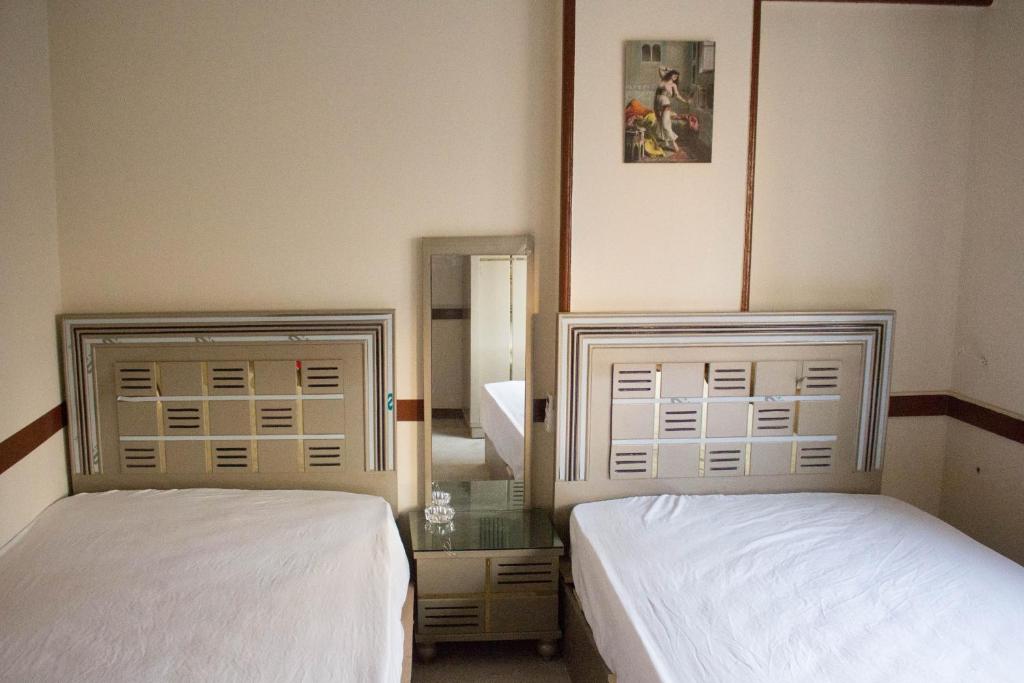 two beds in a hotel room with a mirror at cairo view hotel in Cairo