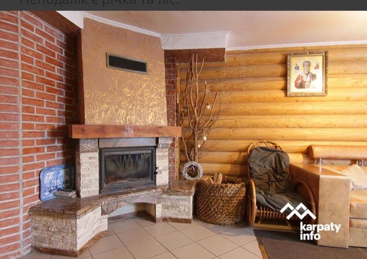 ein Wohnzimmer mit Kamin und Ziegelwand in der Unterkunft Золото Карпат in Izky