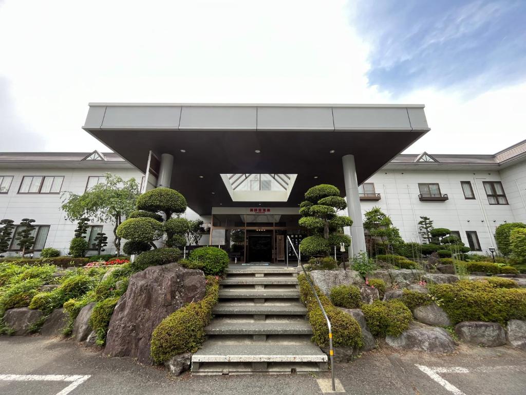 um edifício com escadas em frente a um edifício em Shugyoku no Yu Yakushido Onsen em Oshu