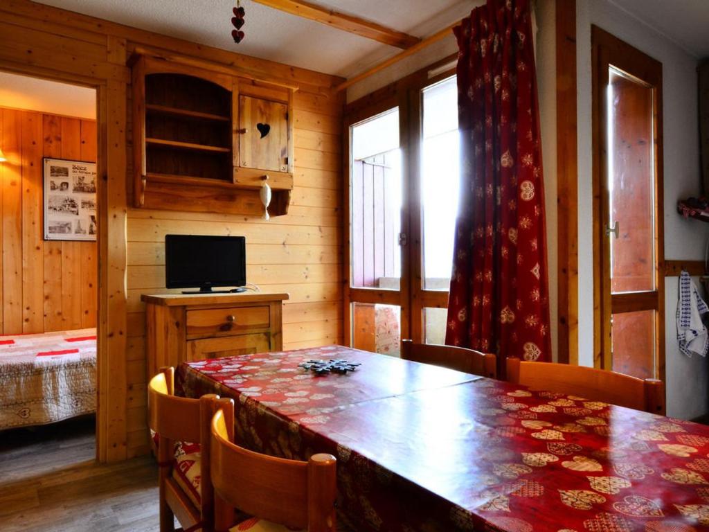 a dining room with a wooden table and a television at Charmant appartement rénové 2/3 pièces pour 5 pers, proche pistes et commerces, parking gratuit - FR-1-329-29 in Bellentre