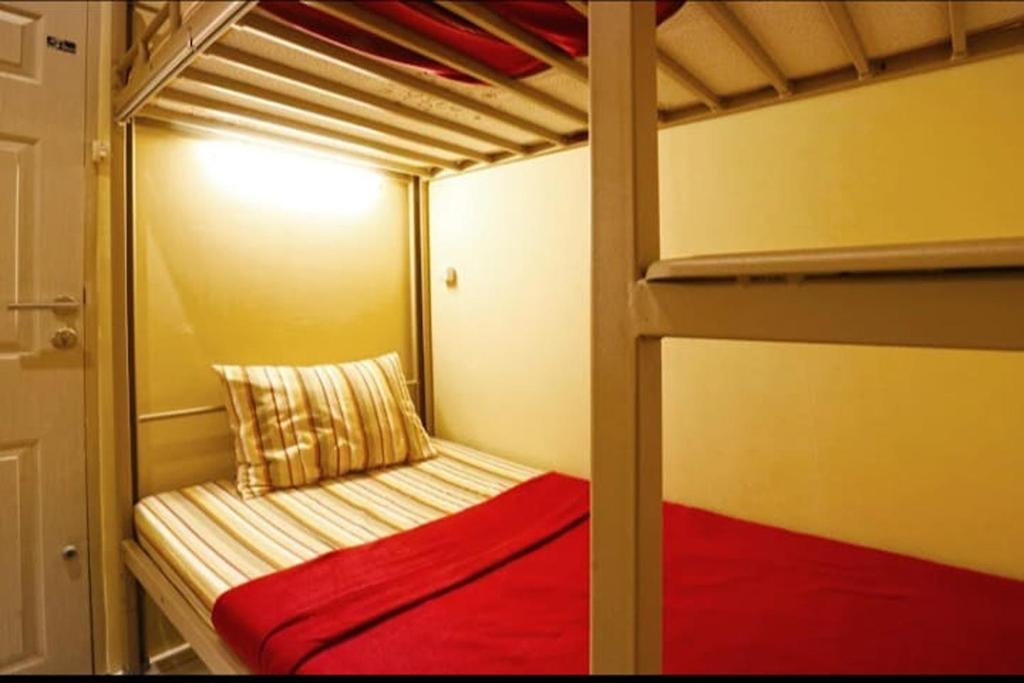 Pondok Backpacker City Square Malang في Bunul: غرفة نوم بسريرين بطابقين مع سرير احمر