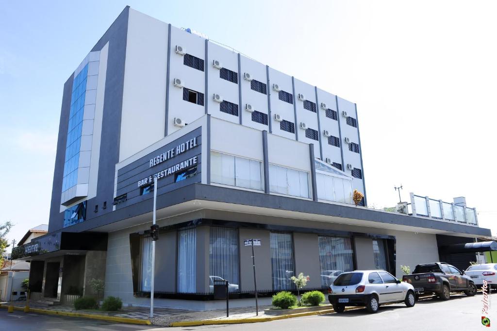 a building with cars parked in a parking lot at Regente Hotel in Unaí