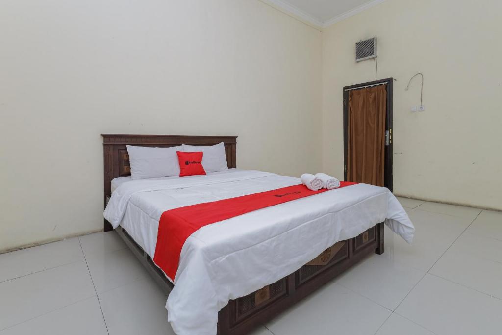 a bedroom with a large bed with a red blanket at RedDoorz Plus near Museum Angkut Batu 4 in Batu