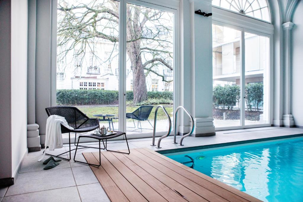 een woonkamer met een zwembad en stoelen en een tafel bij Pillows Grand Boutique Hotel Reylof Ghent in Gent