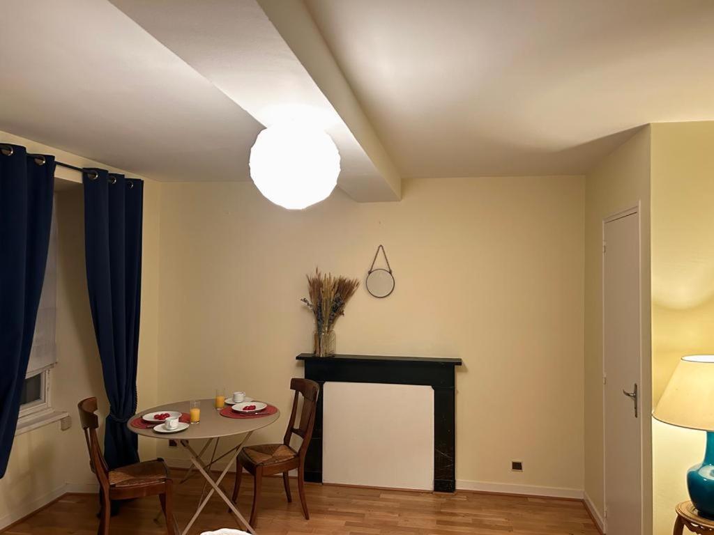ein Wohnzimmer mit einem Tisch und einem Kamin in der Unterkunft Studio dans une grande maison médiévale au centre historique de Laval in Laval