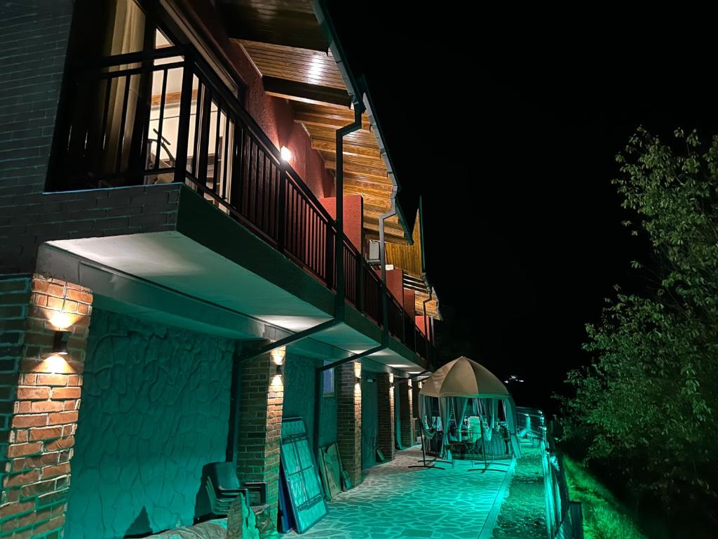 un edificio con balcone e patio di notte di Pesvebi Design Hotel and Cellar a Borjomi