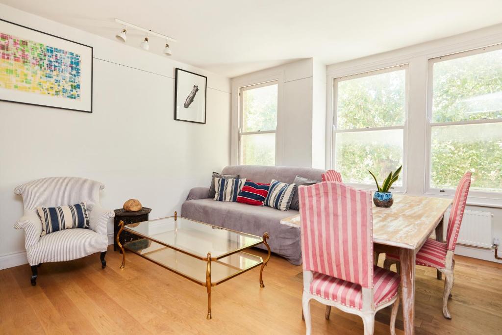 a living room with a couch and a table and chairs at The Hampstead Heath Escape - Trendy 1BDR Flat with Balcony in London