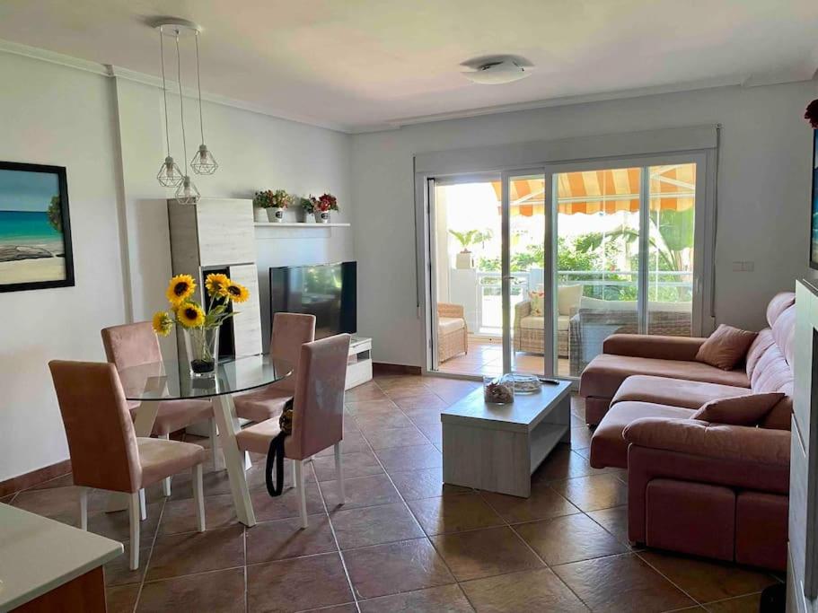 ein Wohnzimmer mit einer Couch und einem Tisch mit Stühlen in der Unterkunft Piso en primera línea de playa, Vera Playa in Playas de Vera
