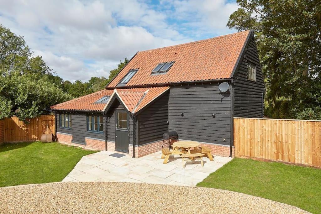 a small house with a picnic table in a yard at Butler's Barn in Newmarket