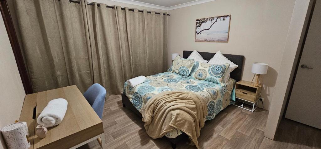 a small bedroom with a bed and a table at Spacious 5-bed house opposite IGA & Golf Course in Kalgoorlie
