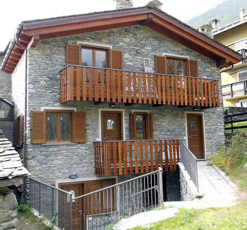 Cette maison en pierre dispose d'un balcon en bois. dans l'établissement Alpini Apartments, à Chiesa in Valmalenco