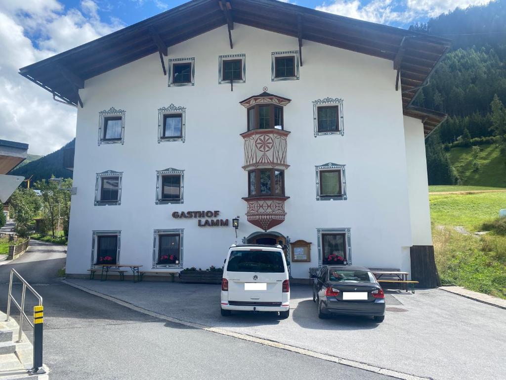 un gran edificio blanco con coches estacionados frente a él en Gasthof Lamm, en Sankt Jodok am Brenner