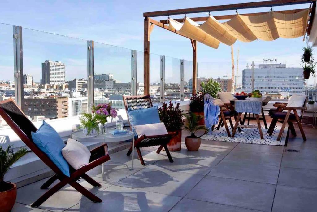 a balcony with chairs and tables and a view of a city at Ático con espectacular terraza en Bernabéu in Madrid