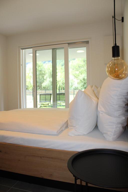ein Bett mit weißen Kissen, einem Tisch und einem Fenster in der Unterkunft Dinaro Suite, Sauna & Garden in Franzensfeste