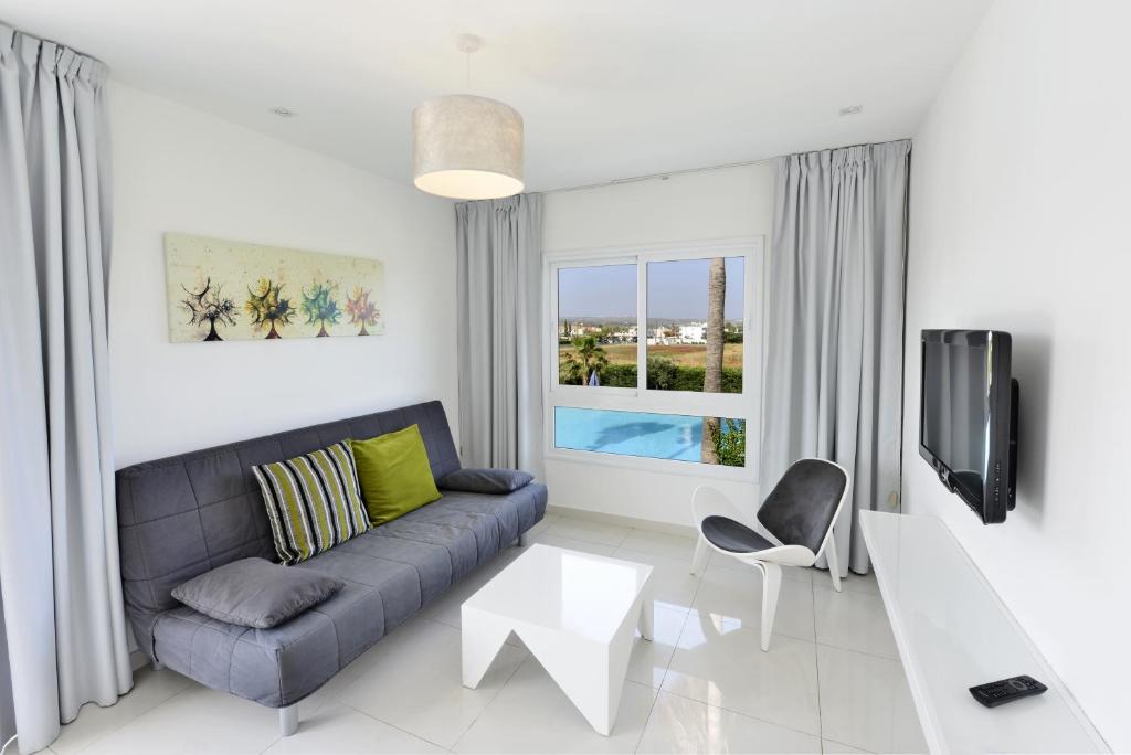 a living room with a couch and a table and a tv at Mon Repos Hotel in Ayia Napa