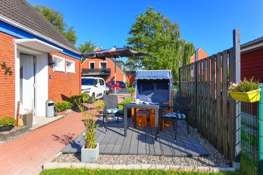 Un patio con mesa y sillas y una valla. en Ferienwohnung Ankerplatz im Gästehaus Kock, en Neuharlingersiel