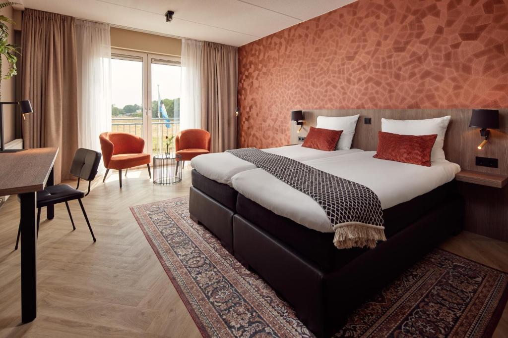 a hotel room with a large bed and a desk at Van der Valk Texel - De Koog in De Koog