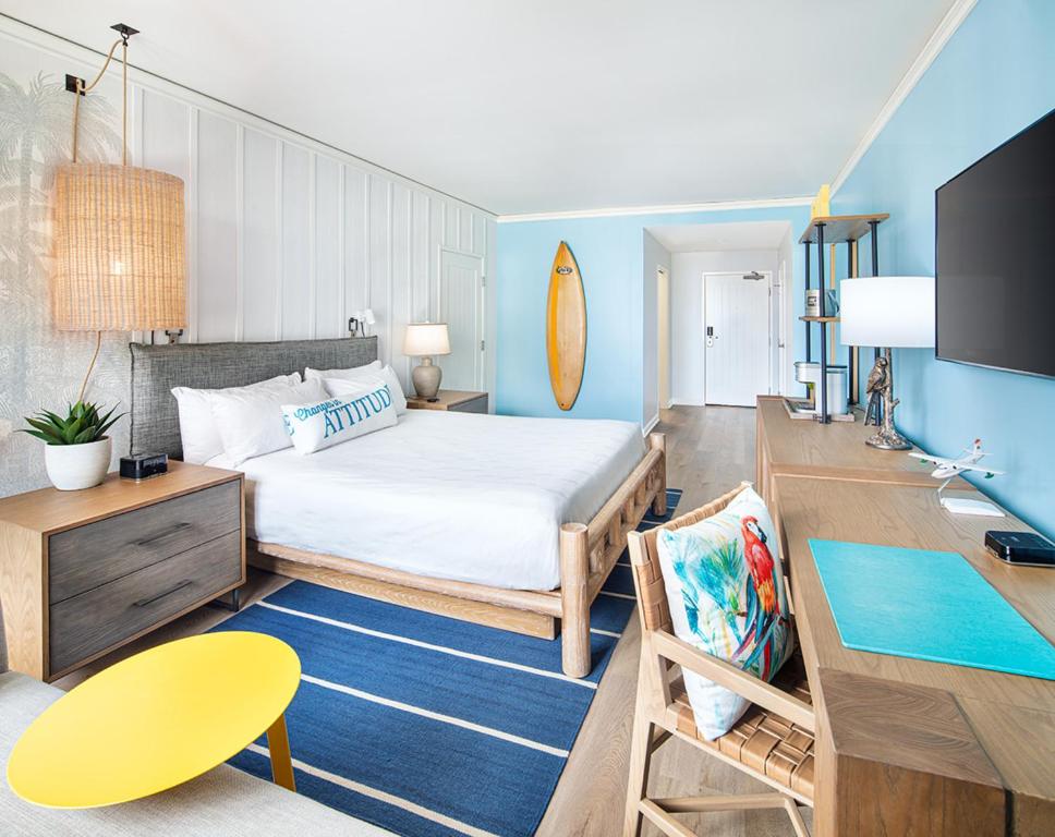 a bedroom with a bed and a desk and a table at Margaritaville Hotel San Diego Gaslamp Quarter in San Diego