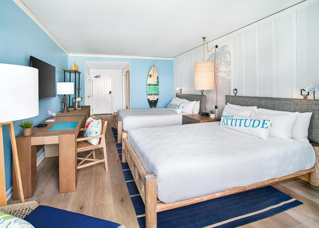 a hotel room with two beds and a desk and a room at Margaritaville Hotel San Diego Gaslamp Quarter in San Diego