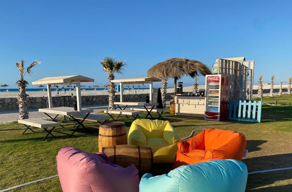 park z kolorowymi krzesłami i stołami na plaży w obiekcie شاليه قرية قرطاج الساحل الشمالي w mieście El Alamein