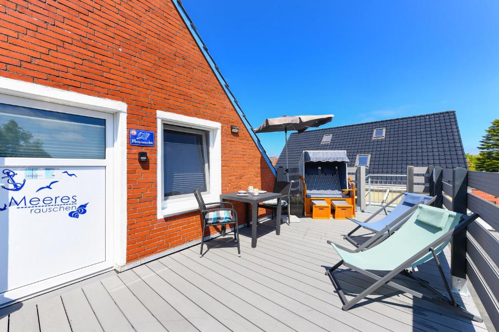 eine Terrasse mit Stühlen, einem Tisch und einem Gebäude in der Unterkunft Apartment Meeresrauschen im Gästehaus Kock in Neuharlingersiel