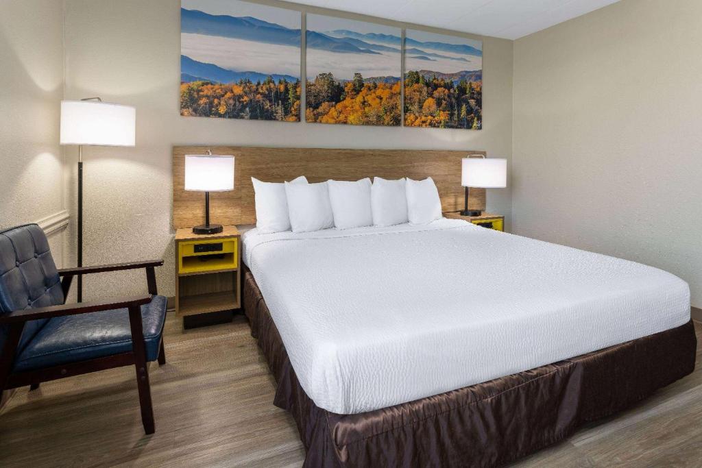 a hotel room with a large bed and a chair at Days Inn by Wyndham Winchester in Winchester