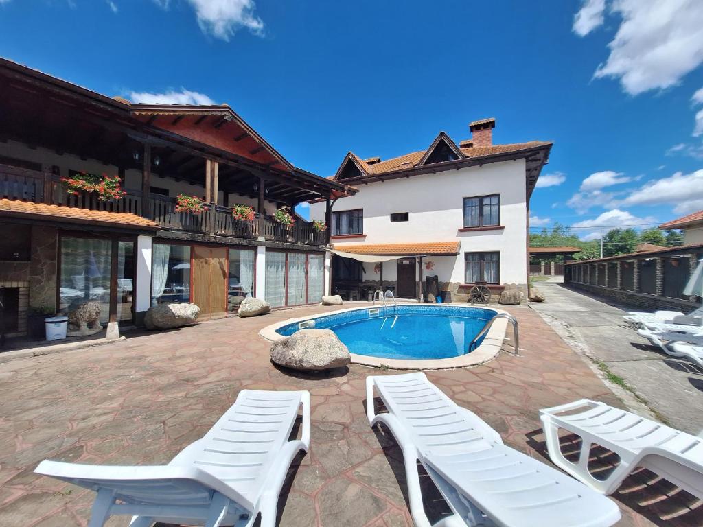 a patio with white chairs and a swimming pool at Къща за гости Бащин дом in Apriltsi