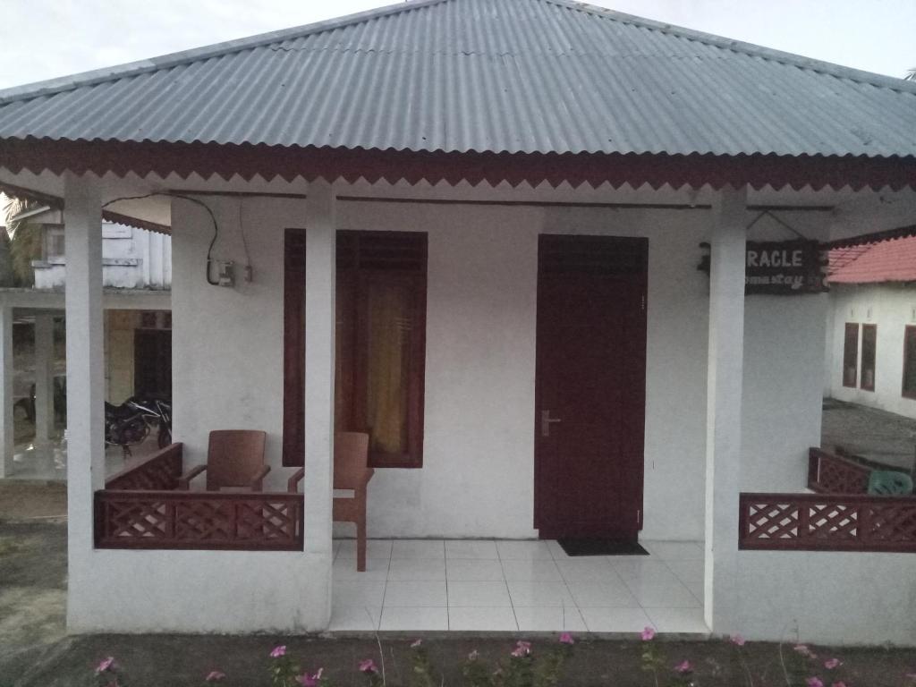 Casa blanca pequeña con porche y sofá en Homestay Miracle, en Rinondoran