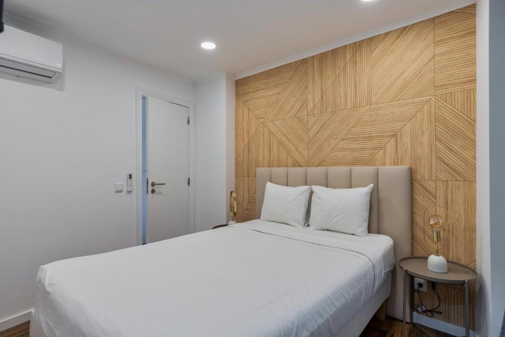 a bedroom with a white bed and a wooden headboard at Bonneville Setúbal I, By Home Match in Setúbal