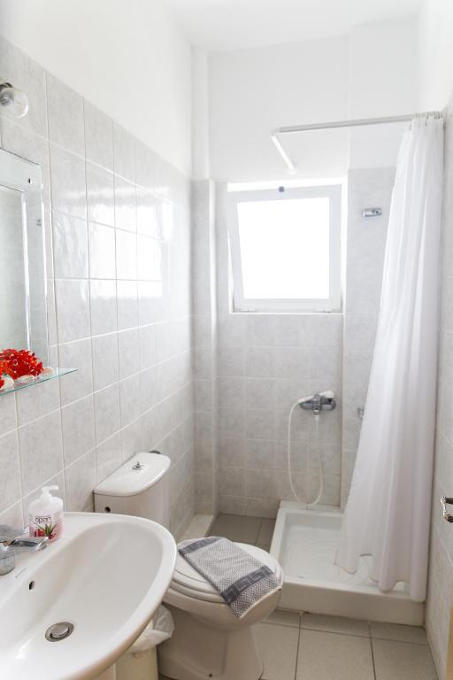 biała łazienka z umywalką, toaletą i wanną w obiekcie Kalami Rooms w mieście Falasarna