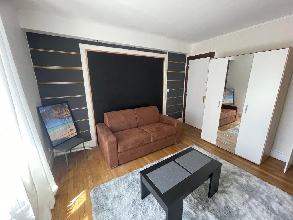 een woonkamer met een bank en een tafel bij Chambre d’hôte proche gare et centre 1 in Besançon