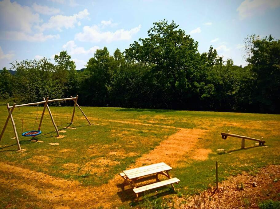 a park with a bench and swings in a field at Le Havre du Circuit / Triplex avec Sauna in Malmedy