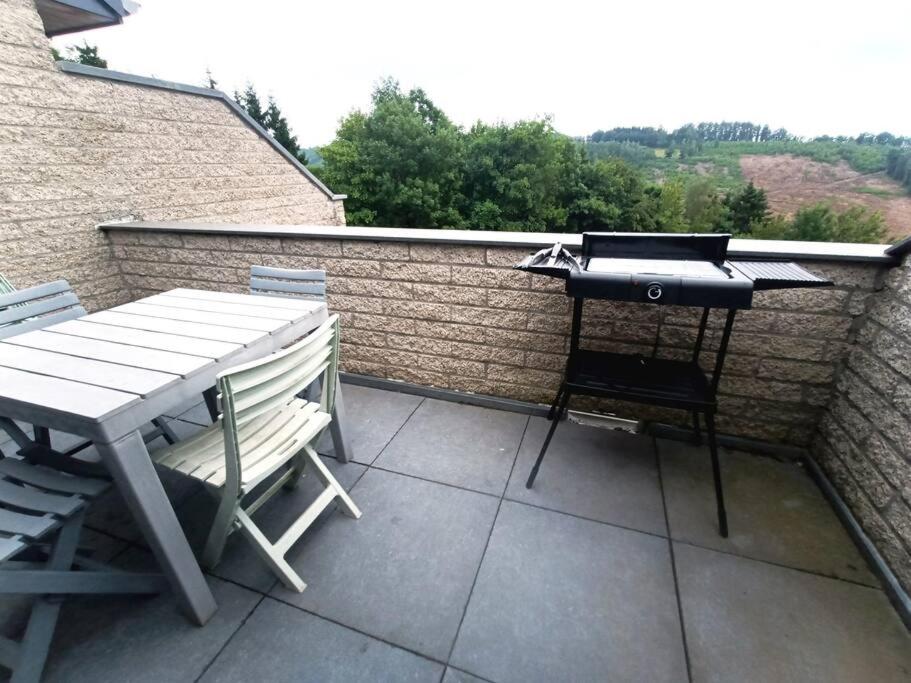 a barbecue grill on a patio with a table and chairs at Le Havre du Circuit / Triplex avec Sauna in Malmedy